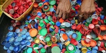  Manos de una persona separando tapas de botellas de plástico