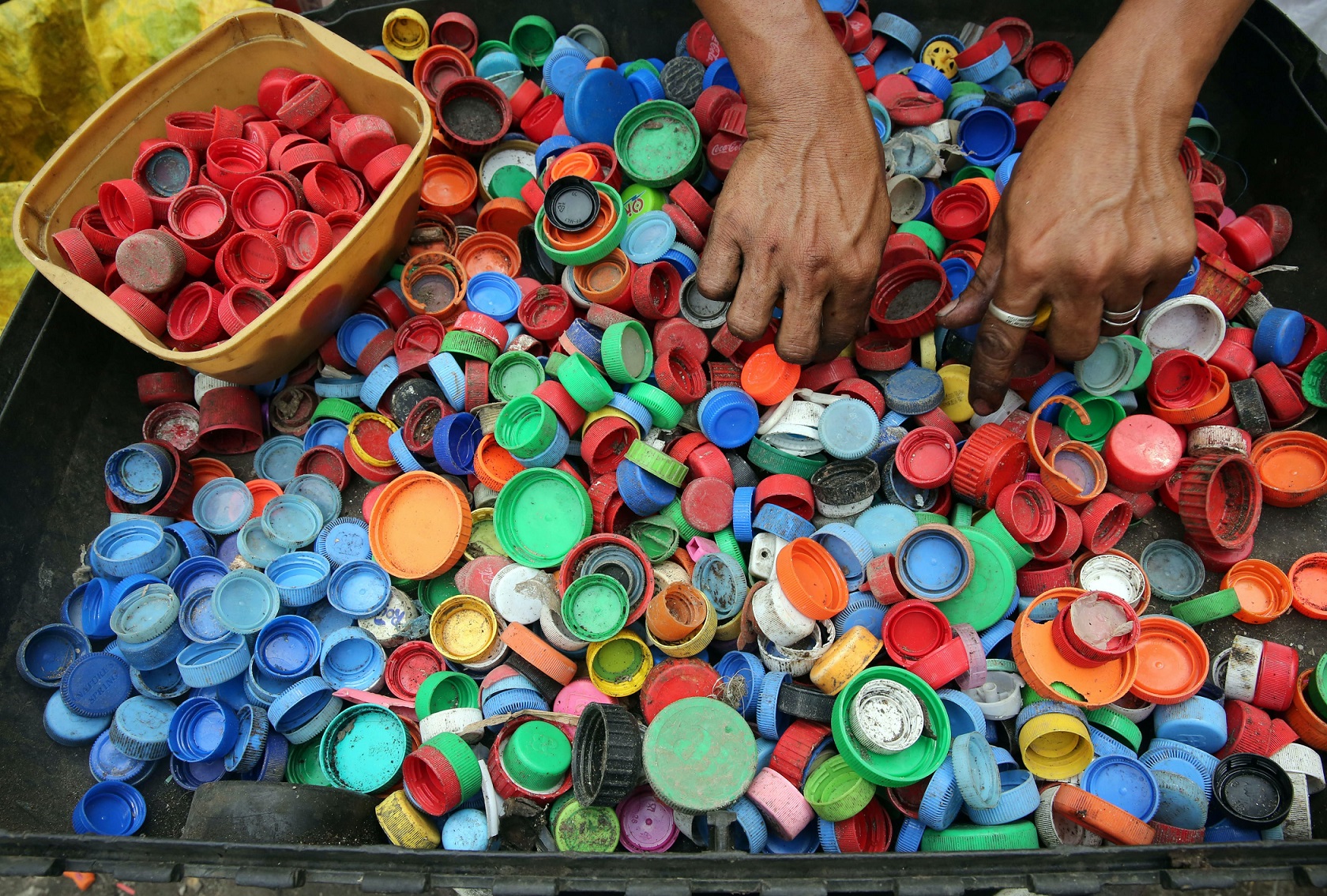  Manos de una persona separando tapas de botellas de plástico