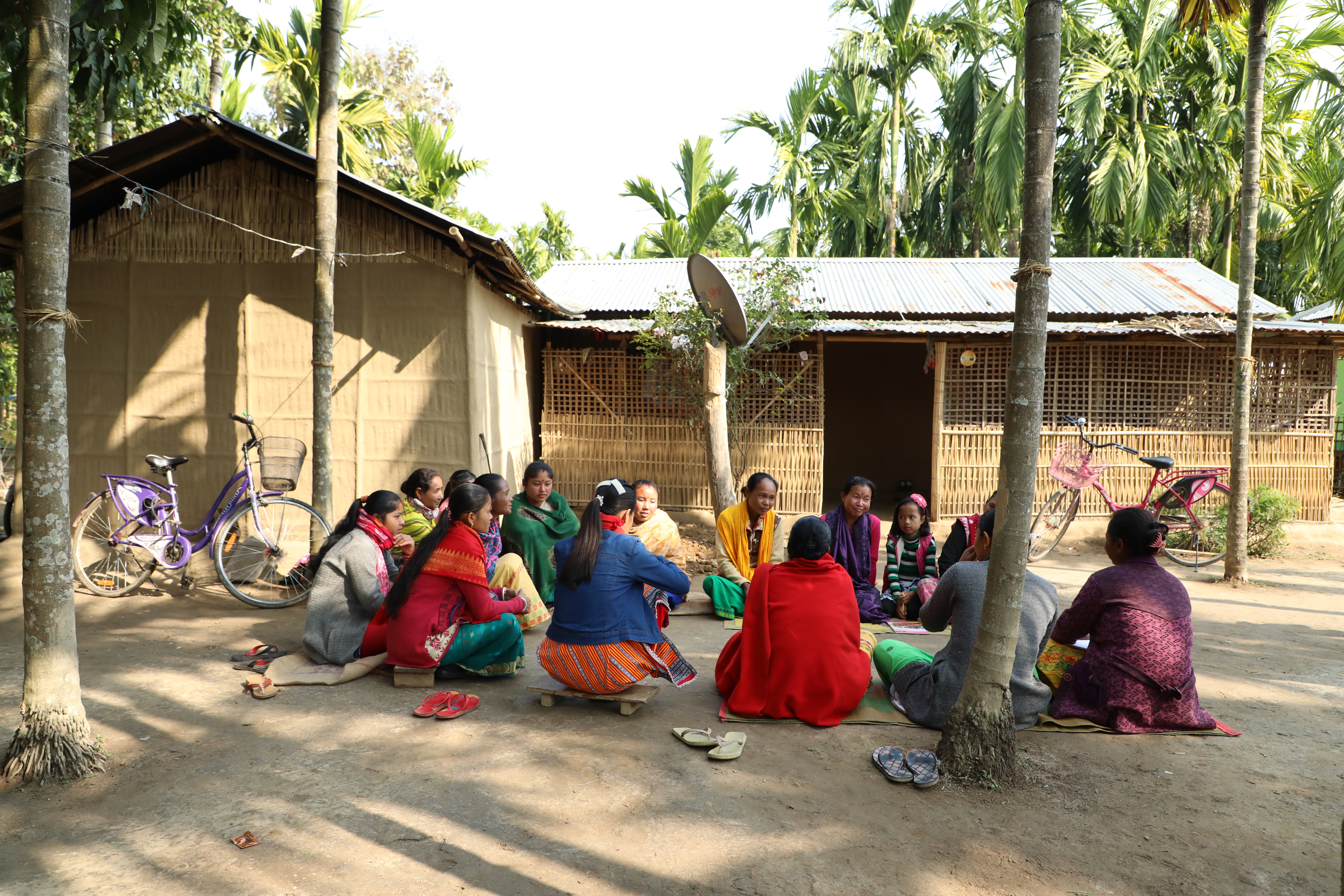 Women from Self-Help Group sitting under tree to hold training with print material 