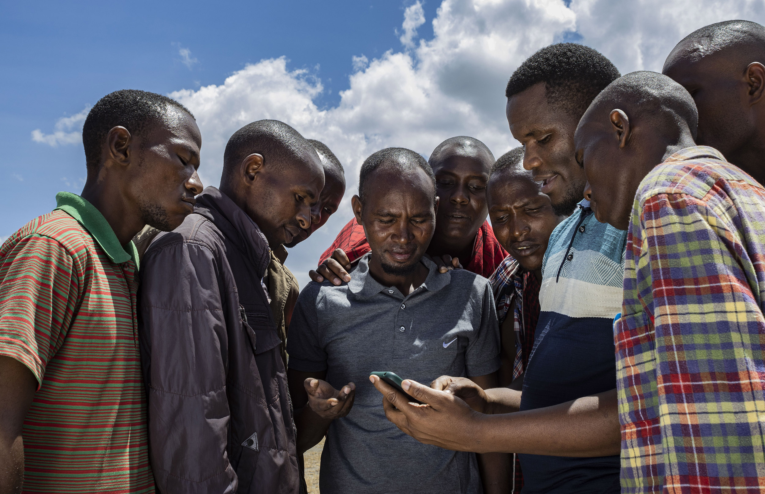 Group of people observe a man using a smartphone