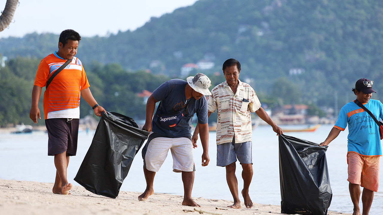 The picture shows four men in a beach cleaning activity. 