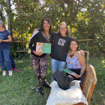In this image, one can see a Ívene, a black young woman standing at the center, holding her certificate from a recent ecotourism workshop. She is surrounded by her two women professors, who are beaming with pride.