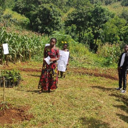 Peace Kamuyambeni (in dress) welcomes attendees to a field day