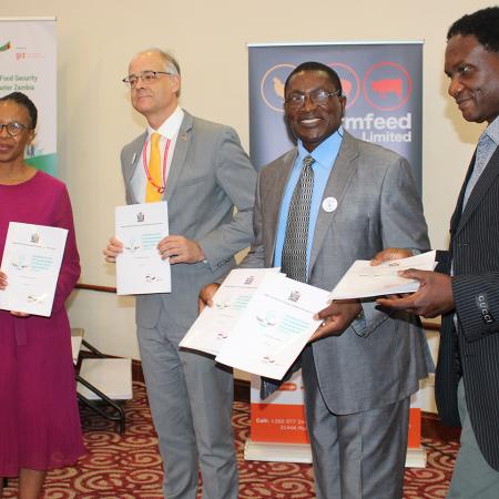 Four smiling people holding certification documents into the camera.