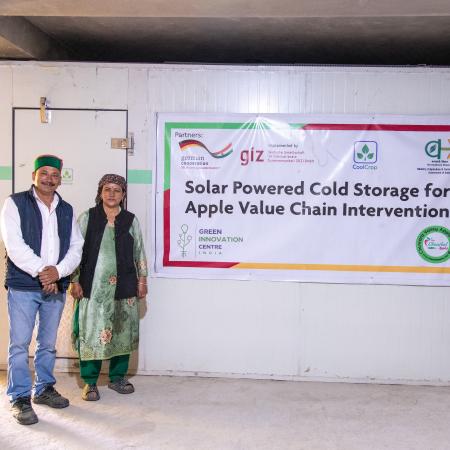 Birendar Bashata and his wife, apple farmers from Shiladesh village in Himachal Pradesh, standing in front of the cold storage installed by GIC India under the 'Cooling as a Service' Business model