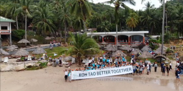 The picture shows a group of participants at a beach holding the "Koh Tao Better Together" campaign sign 