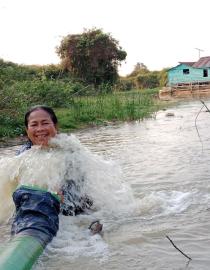 Cambodian lady adjusts flowing water pipe in a fish conservation pond.