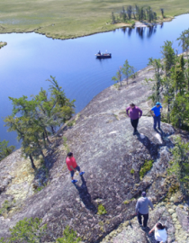 Image aérienne d'élèves à Kinosao Sipi, Manitoba. Les élèves grimpent sur un rocher et on aperçoit une rivière au loin.